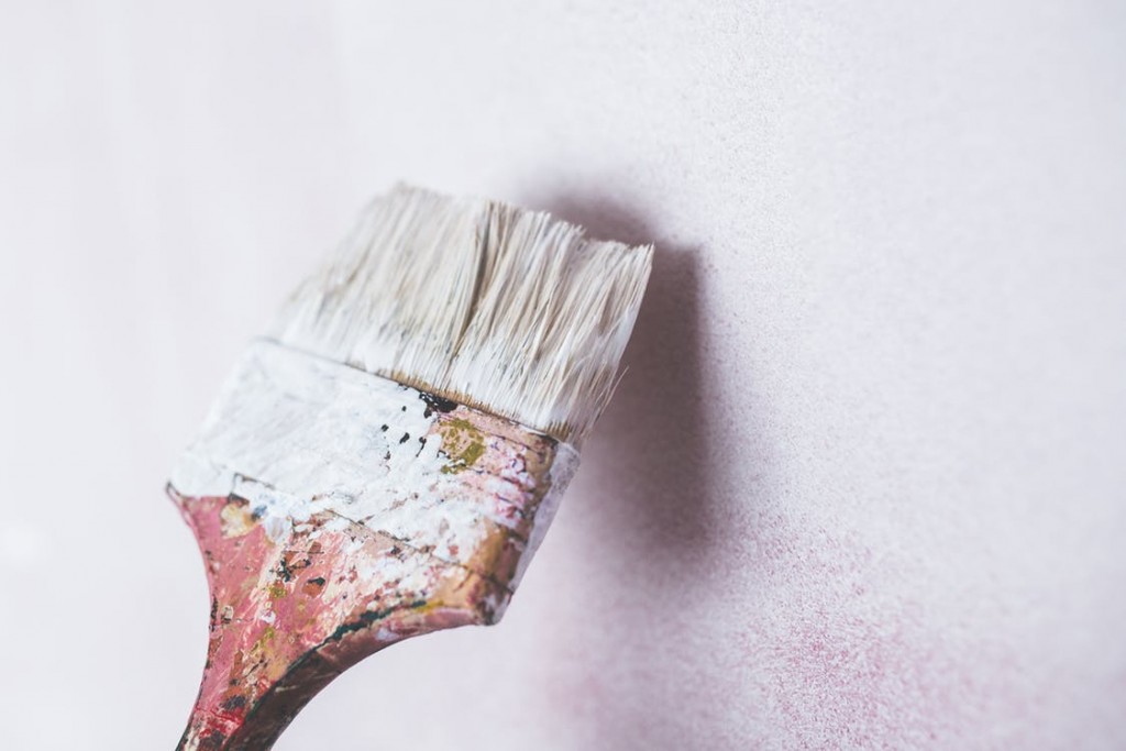 a large paintbrush coating a wall with white paint