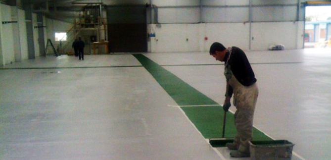 Image of a man painting a warehouse floor